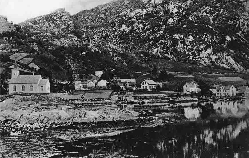 Bruvik 1905. Til høgre for kyrkja gamletunet på Kyrkje-Bruvik. Grensa mellom Kyrkje-Bruvik og Indre-Bruvik går til venstre for nausta. Attom nausta ligg husa på Bakken (bnr. 4-8 og 10). Gamalt prospektkort.